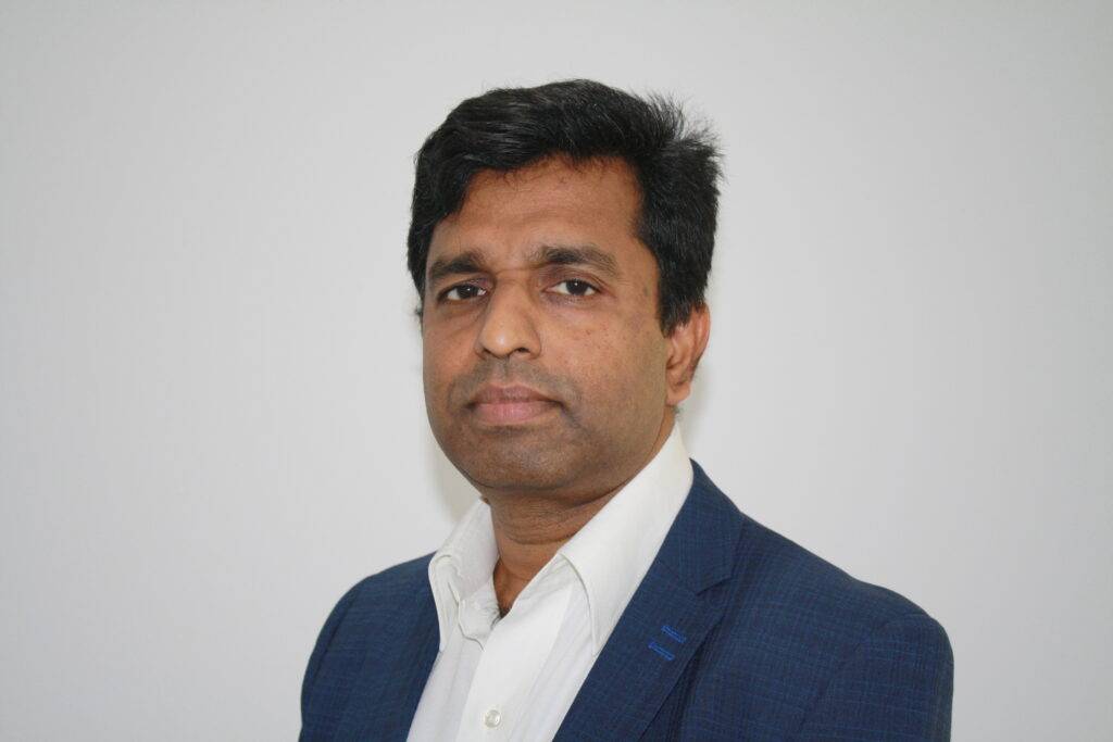 A professional portrait of Jino, a practitioner at the Perth Lymphoedema Clinic, wearing a dark suit and white shirt. He is looking directly at the camera with a neutral expression against a plain white background.